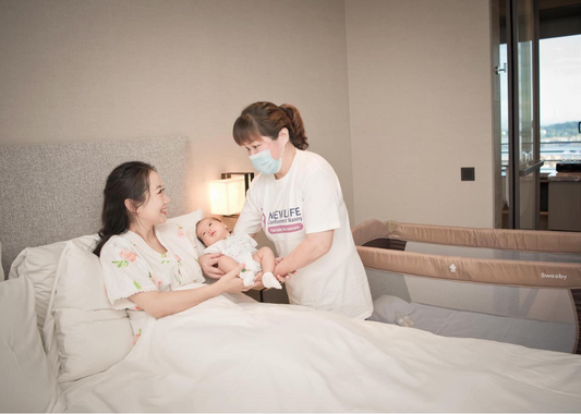 post partum mom on bed handing baby to care taker